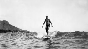 Duke Kahanamoku surfing with Diamond Head at left in the background on Oahu Island in the Hawaiian Islands. 